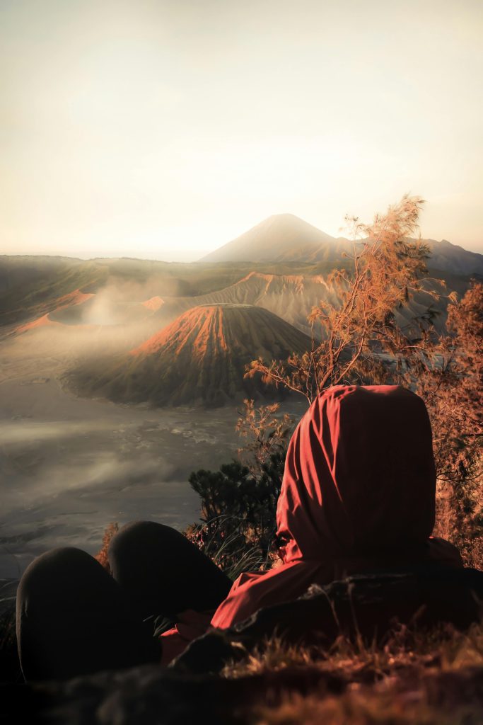 A person in a red headscarf admires the foggy sunrise over Mount Bromo in Indonesia.